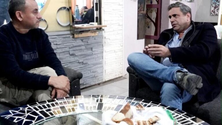 Lisandro Catalán escuchando y comiendo bollo con un vecino de Delfín Gallo
