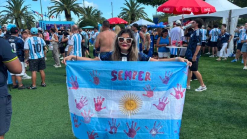 Bandera argentina con huellas de manos rosas sostenida por una mujer en el estadio Hard Rock Stadium