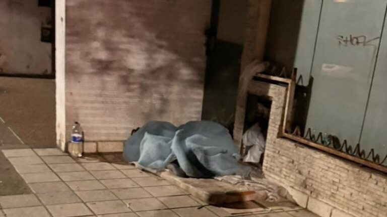 Exequiel y Natalia cubiertos con una colcha en la vereda de San Lorenzo al 200