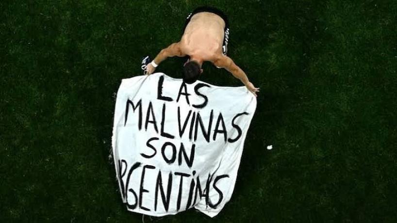 Giovani Lo Celso mostrando una bandera con la leyenda Las Malvinas son argentinas