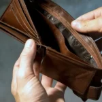 Persona revisando cuentas y billetes sobre una mesa
