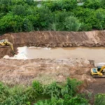 Maquinaria pesada trabajando en la construcción de un terraplén de contención en el río Salí, en Los Vallistos.