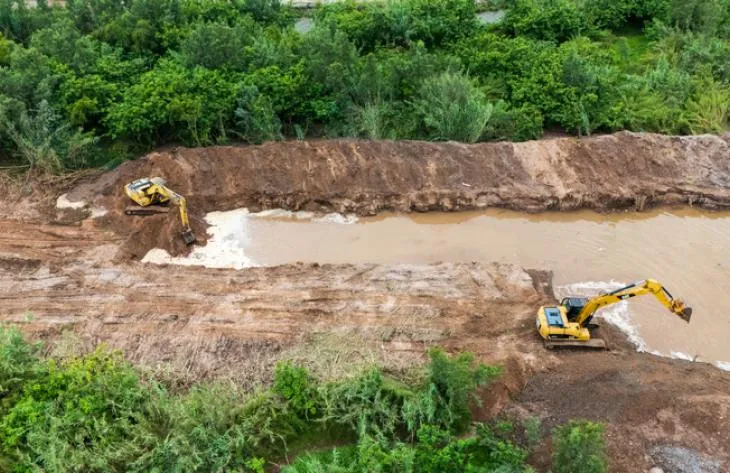 Maquinaria pesada trabajando en la construcción de un terraplén de contención en el río Salí, en Los Vallistos.